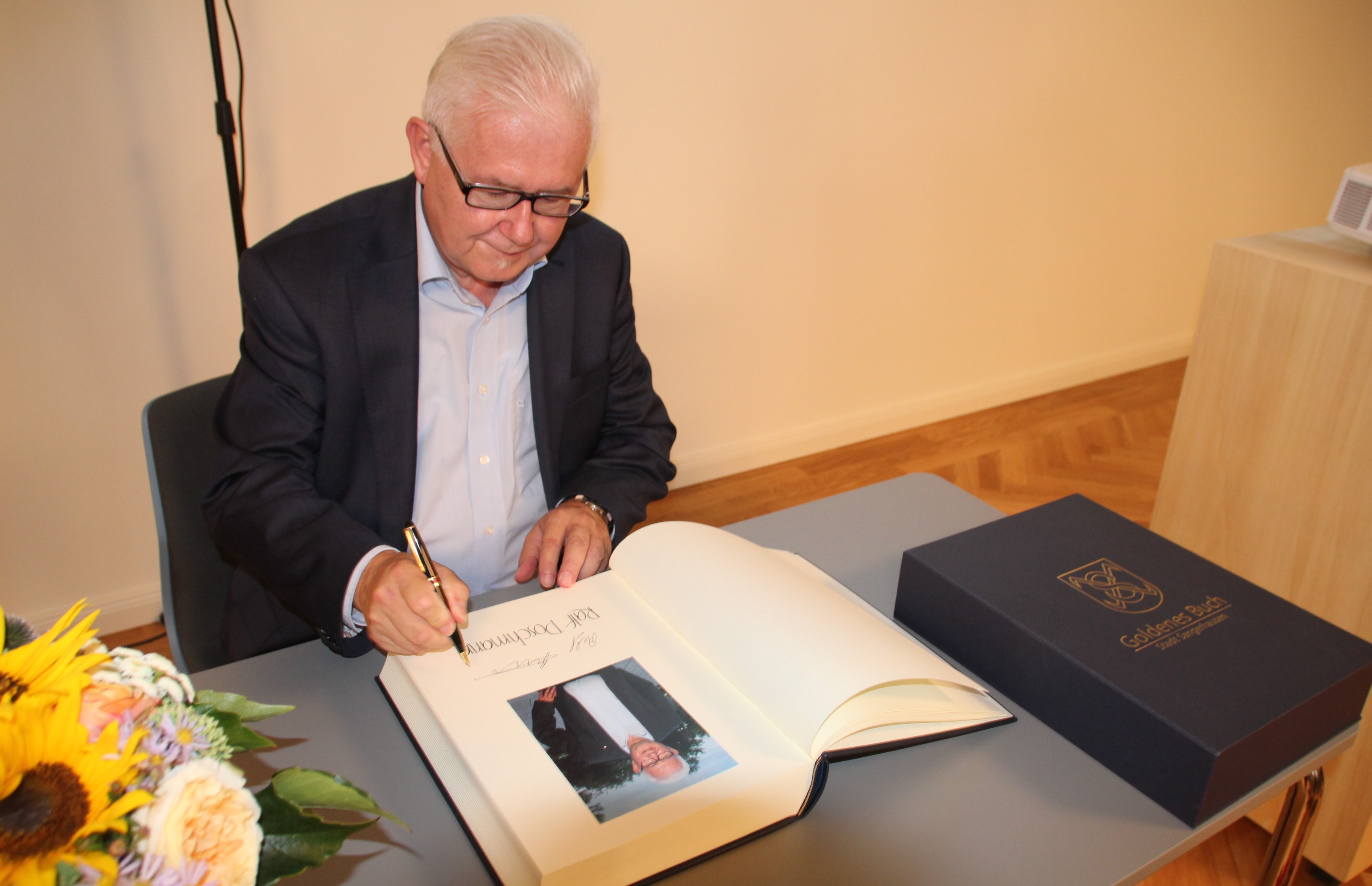 Herr Poschmann trägt sich in das Goldene Buch ein.
